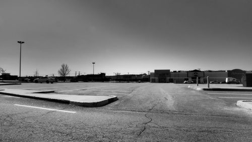 Empty road by buildings against clear sky