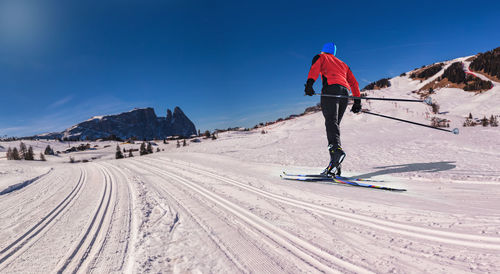 Rear view of person skiing on snowcapped mountain against sky