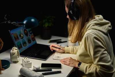 Woman working from home workplace at night, using laptop