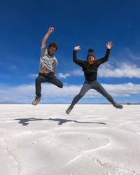 Man and woman jumping at salinas grandes, argentina