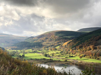 Scenic view of river by mountains against sky