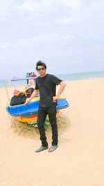 Full length of man standing by boat on sand at beach against sky