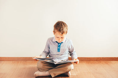 Boy sitting on wooden floor at home