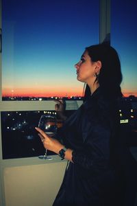 Side view of a woman drinking glass at night