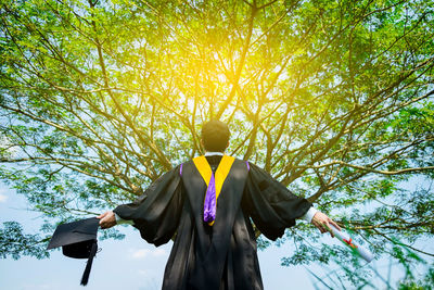 Rear view of man in graduation gown standing against sky