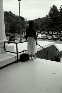 Rear view of woman standing against trees