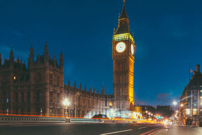 Illuminated clock tower in city at night