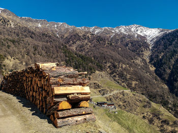 Stack of wood on mountain against alpine farm houses and mountains in val venosta