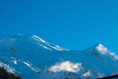 Aerial view of snowcapped mountains against clear blue sky