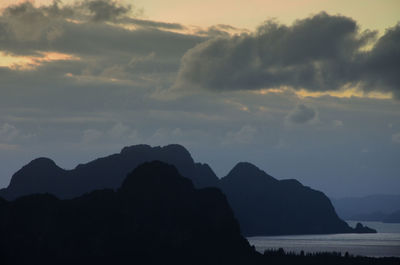 Silhouette mountain by sea against sky at sunset