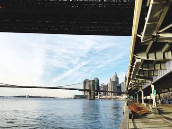 Brooklyn bridge over east river against sky in city