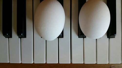 Close-up of white eggs on piano keys