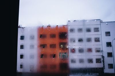 Close-up of wet glass window against sky