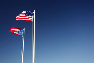 Low angle view of flag flags against clear blue sky