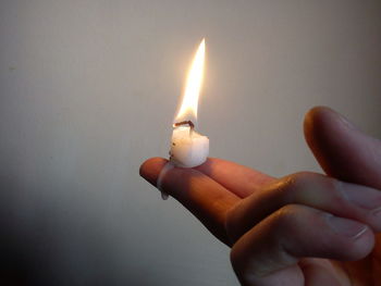 Close-up of hand holding lit candle