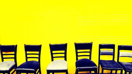 Empty chairs against yellow wall