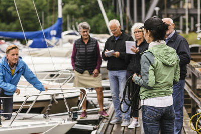 Female instructor holding rope while explaining senior men and women during boat master course