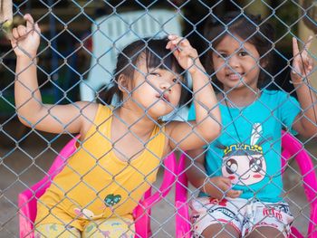 Portrait of smiling girl standing against fence