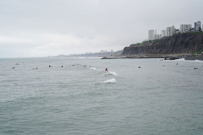 People in sea against sky