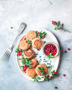 Breakfast set. russian cheese cakes on a craft ceramic plate with lingonberry over a blue background