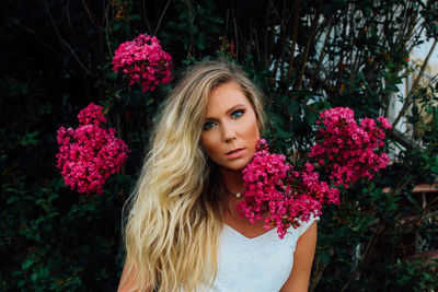 Portrait of beautiful woman standing with pink flowers