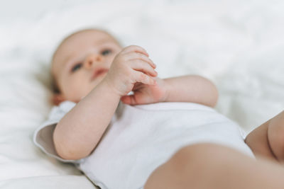 Cute baby girl 2-4 month on the bed with white linen, natural tones, selective focus