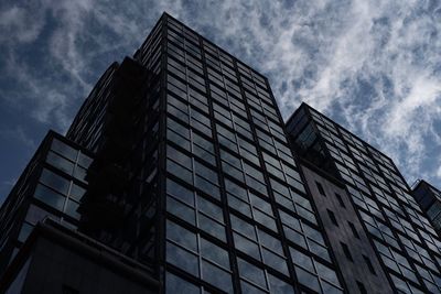 Low angle view of office building against cloudy sky