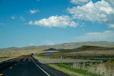 Scenic view of road by mountains against sky