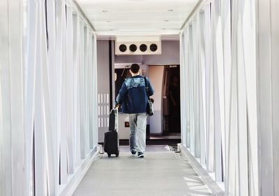 Rear view of man walking in corridor