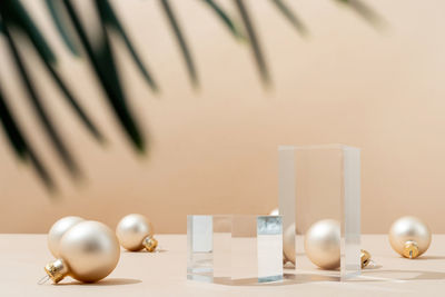 A minimalistic scene of glass podium with christmas pine tree and balls on beige background. 
