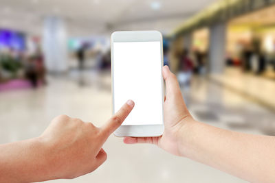 Cropped hands of woman using phone in shopping mall