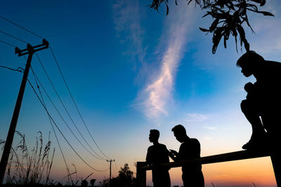 Low angle view of silhouette men against sky during sunset