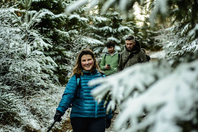 Friends walking amidst trees during winter