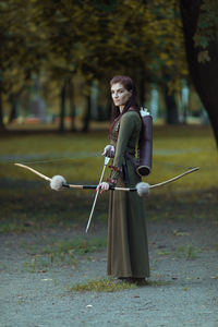 Archer holding bow and arrow while standing outdoors