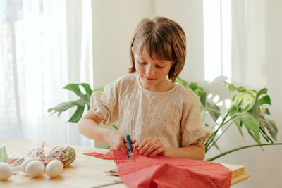 Making easter eggs in the shape of a hare from textile. the girl prepares the fabric