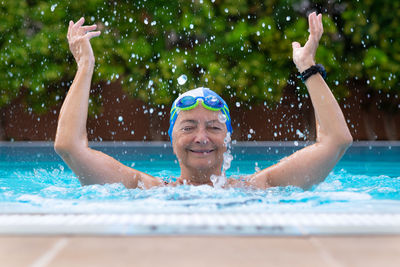 Portrait of happy senior woman swimming in pool