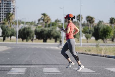 Full length of woman running on road against sky