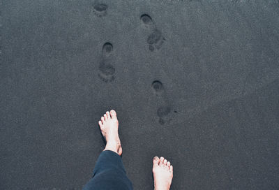 Low section of person standing on sand at beach