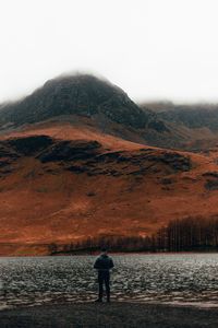 Rear view of man standing on mountain against sky