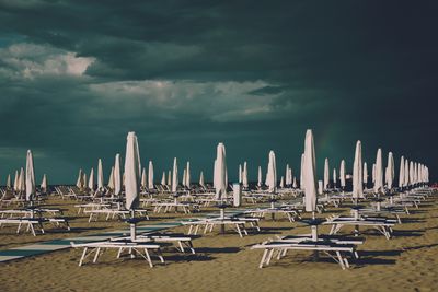 Long chairs and beach umbrellas against dramatic sky
