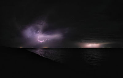 Scenic view of lightning over sea against sky at night