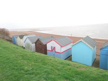 Hooded beach chairs on sand against sky