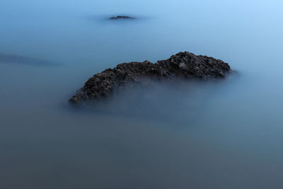 Rock formation in sea against sky