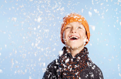 Happy boy against sky during snowfall