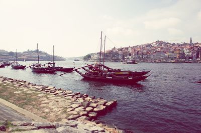 Boats moored in sea against sky in city