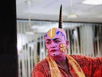 Man with face paint and traditional clothing looking away
