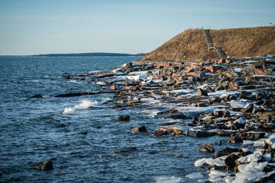 Scenic view of rocky shore against sky during winter