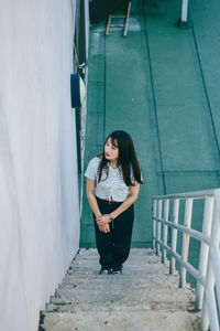 Portrait of woman standing on staircase by railing at building terrace