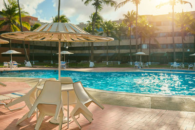 Empty chairs and swimming pool against sky