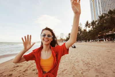 Young woman with arms raised standing at beach